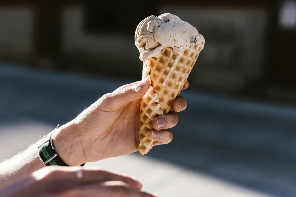 Hand hält eine Eistüte mit einer Kugel Eis
