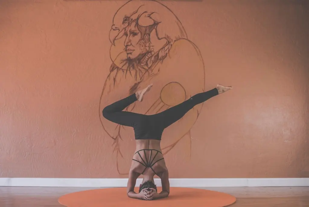 Frau im Kopfstand während einer Yoga-Stunde