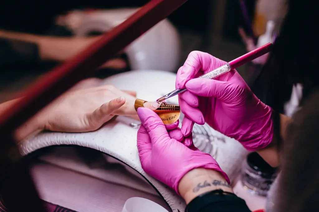 Nageldesignerin trägt Nagellack mit feinem Pinsel auf